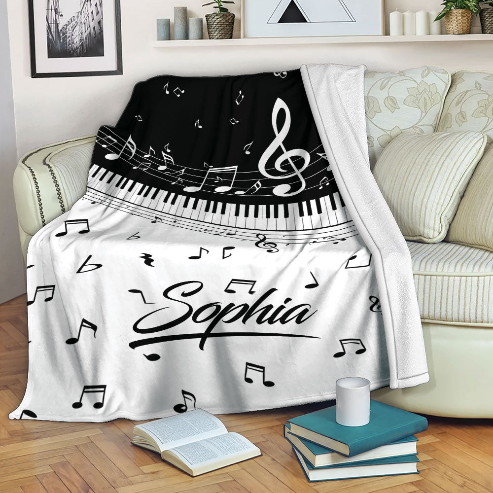 Piano throw blanket draped over a sofa with keyboard keys, musical notes, and black and white design