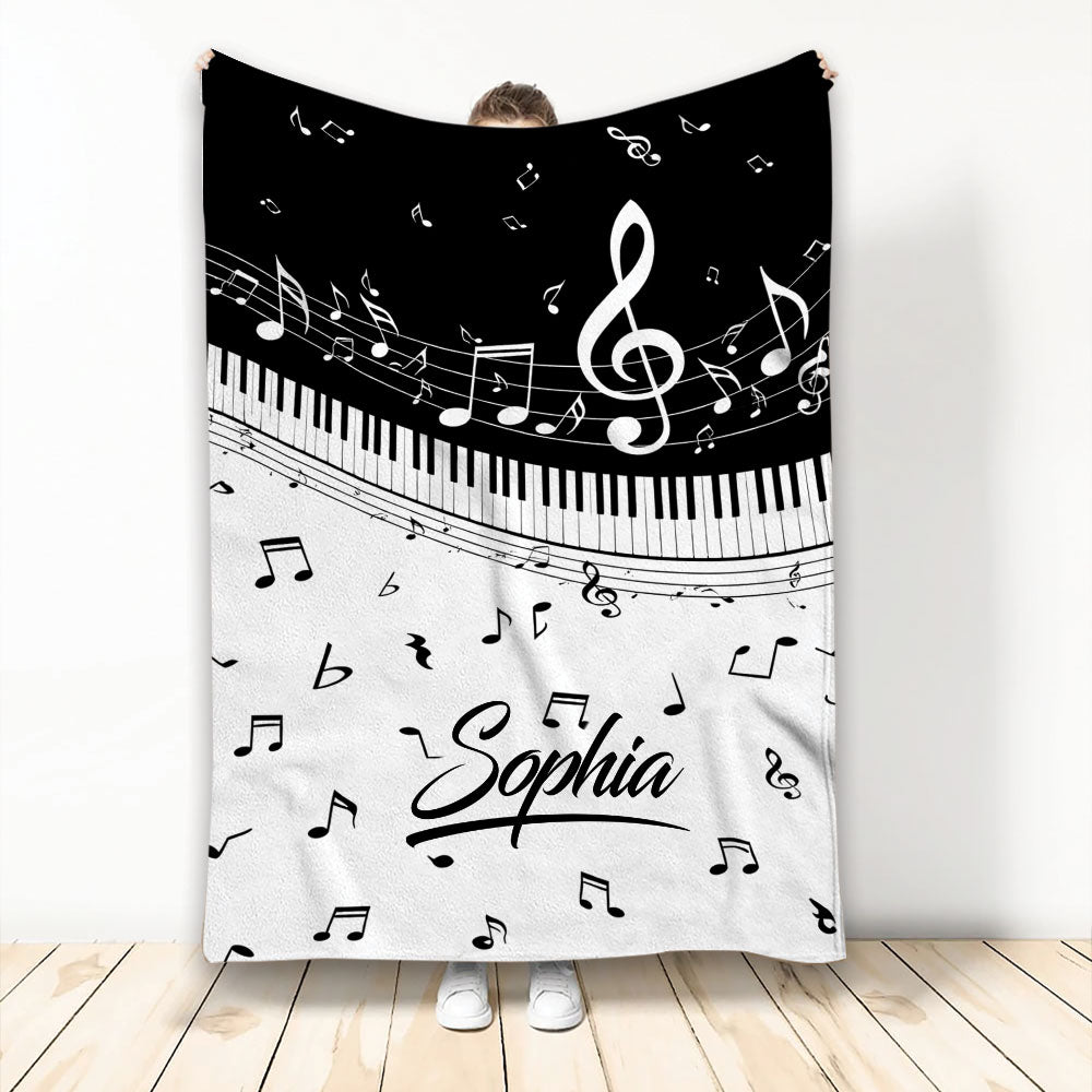 Piano throw blanket displayed vertically with black and white keys, musical notes, and treble clef artwork