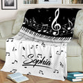 Black and white piano throw blanket styled on a couch with sheet music and treble clef details