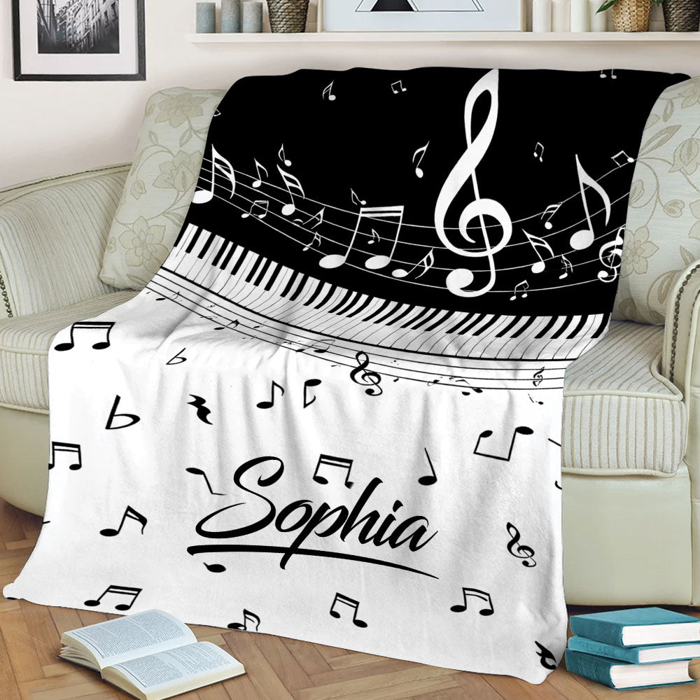 Black and white piano throw blanket styled on a couch with sheet music and treble clef details
