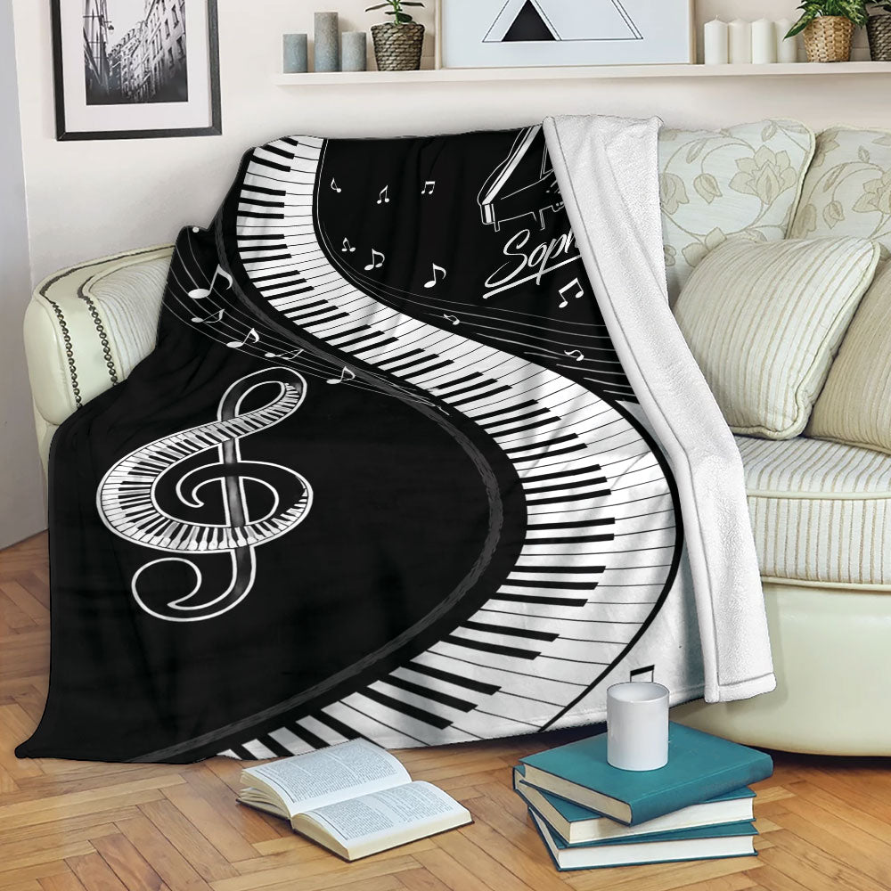 Piano throw blanket draped over a sofa with keyboard keys, music notes, and black and white musical artwork
