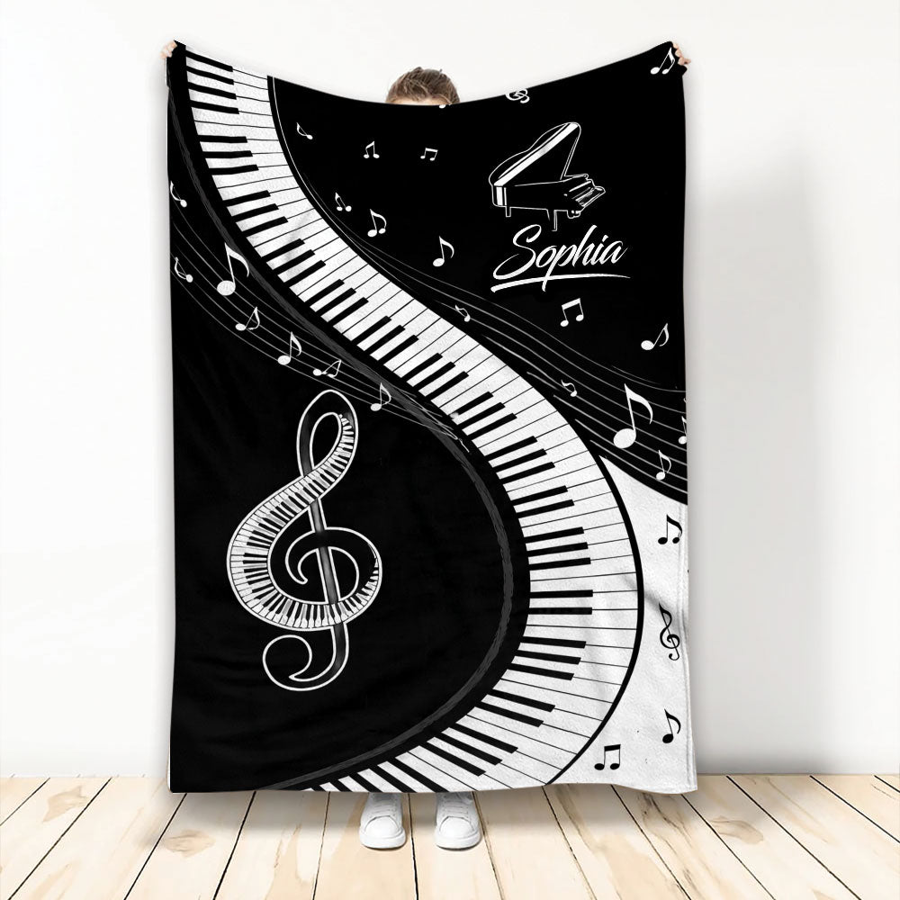 Black and white piano throw blanket with sweeping keyboard keys, musical notes, grand piano, and treble clef artwork