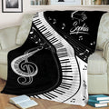 Black piano blanket displayed on a sofa with curved keyboard artwork, grand piano design, musical notes, and treble clef