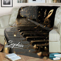 Piano throw blanket displayed across a sofa, featuring dramatic black and gold keys with floating music notes
