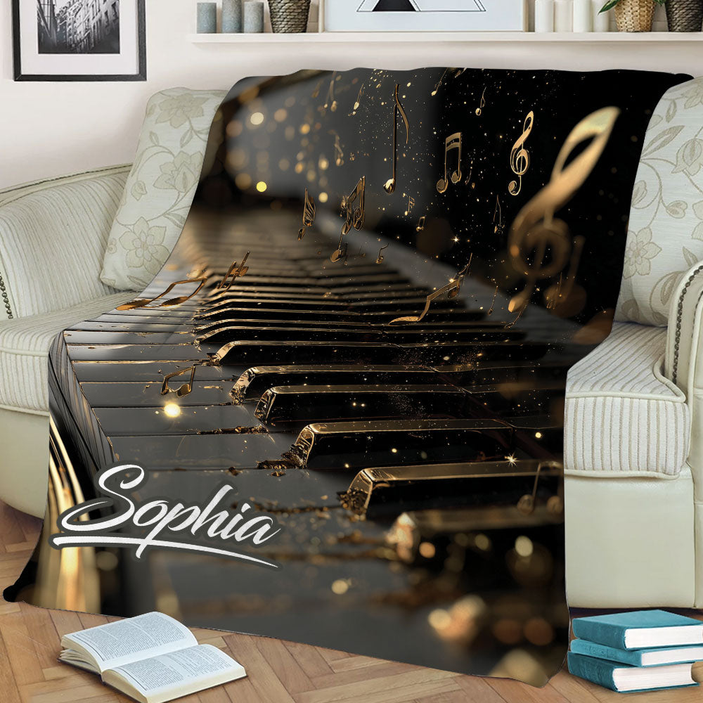 Piano throw blanket displayed across a sofa, featuring dramatic black and gold keys with floating music notes