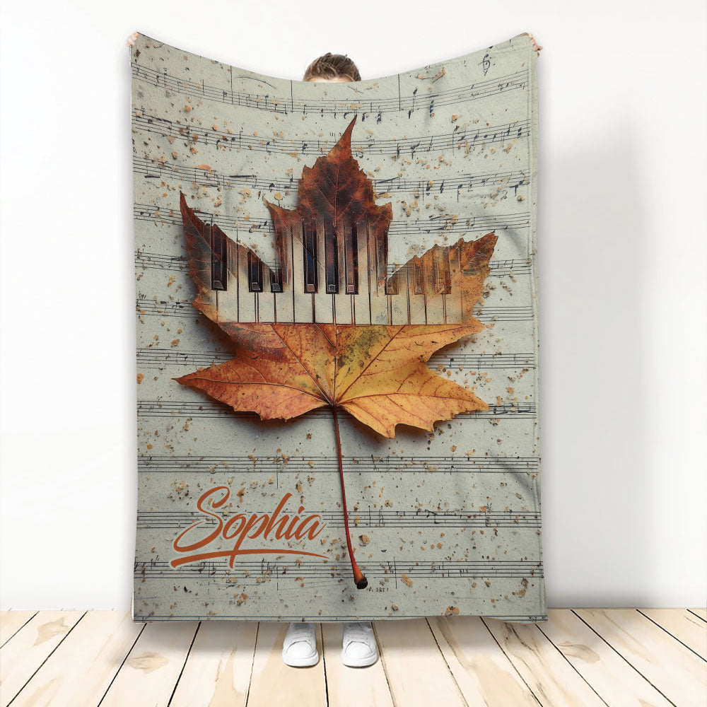 Piano throw blanket featuring piano keys, sheet music, and an autumn maple leaf design