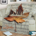 Autumn piano blanket displayed on a sofa with maple leaf artwork and musical notes