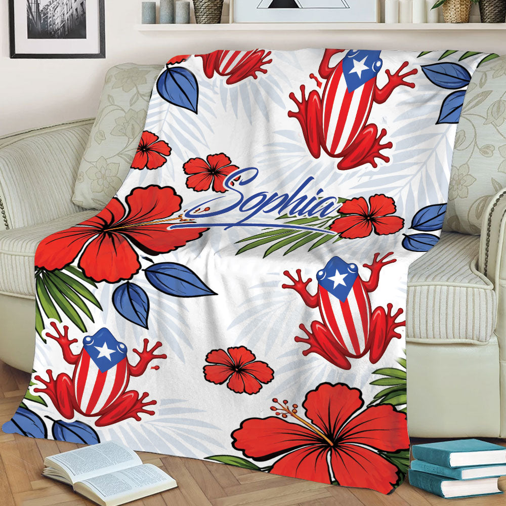 Puerto Rico throw blanket displayed on a couch with red hibiscus flowers, tropical leaves, and patriotic frog artwork