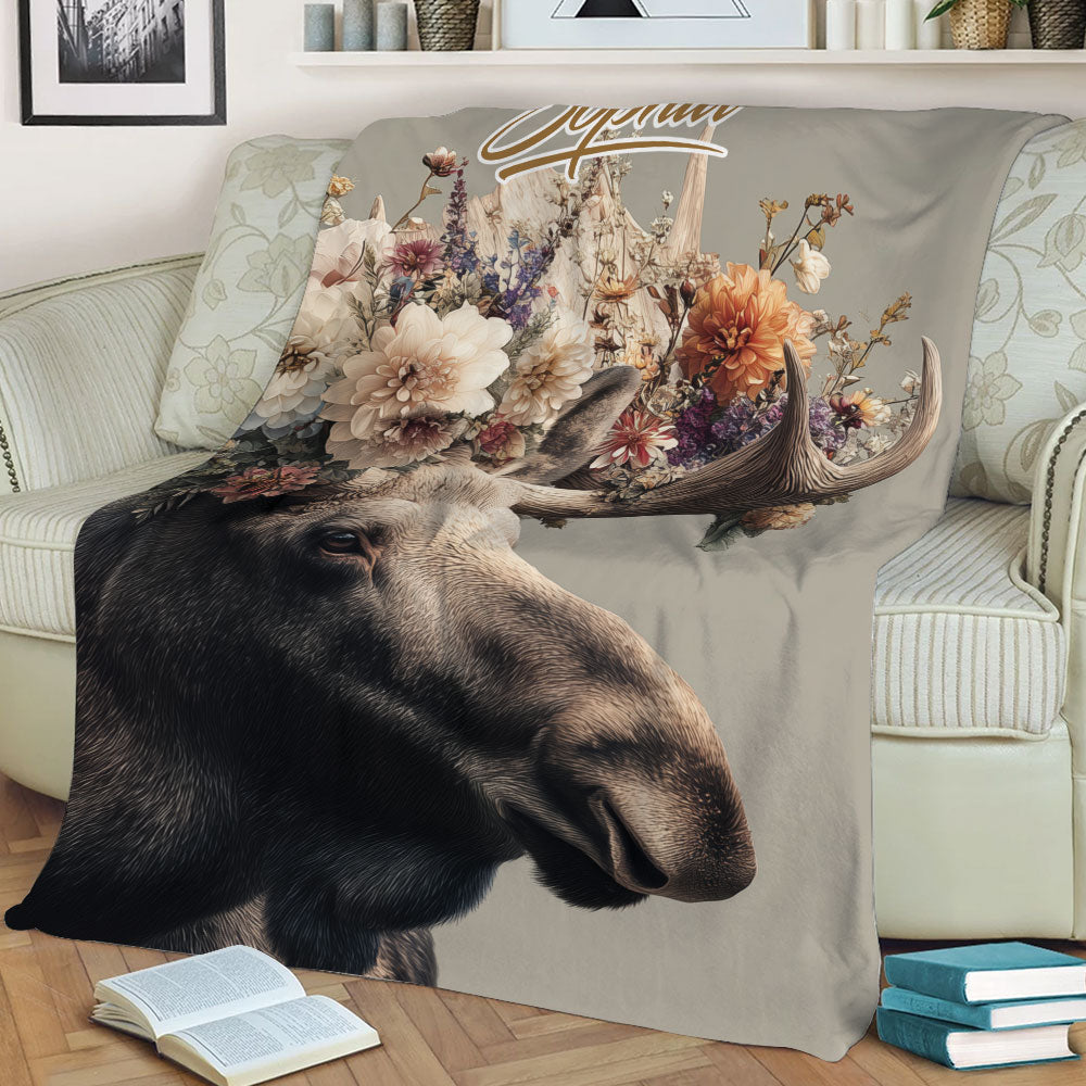 Close-up floral moose blanket featuring detailed antlers and wildlife artwork on a sofa