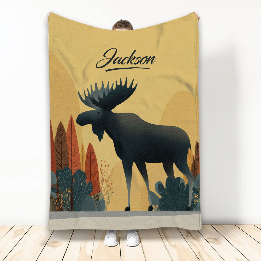 Moose throw blanket with a bold illustrated wildlife design, warm golden background, and woodland foliage