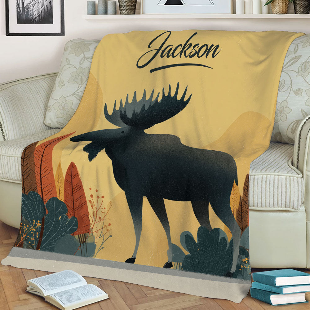 Close view of a moose throw blanket displayed on a sofa with rustic forest artwork and warm earthy colors