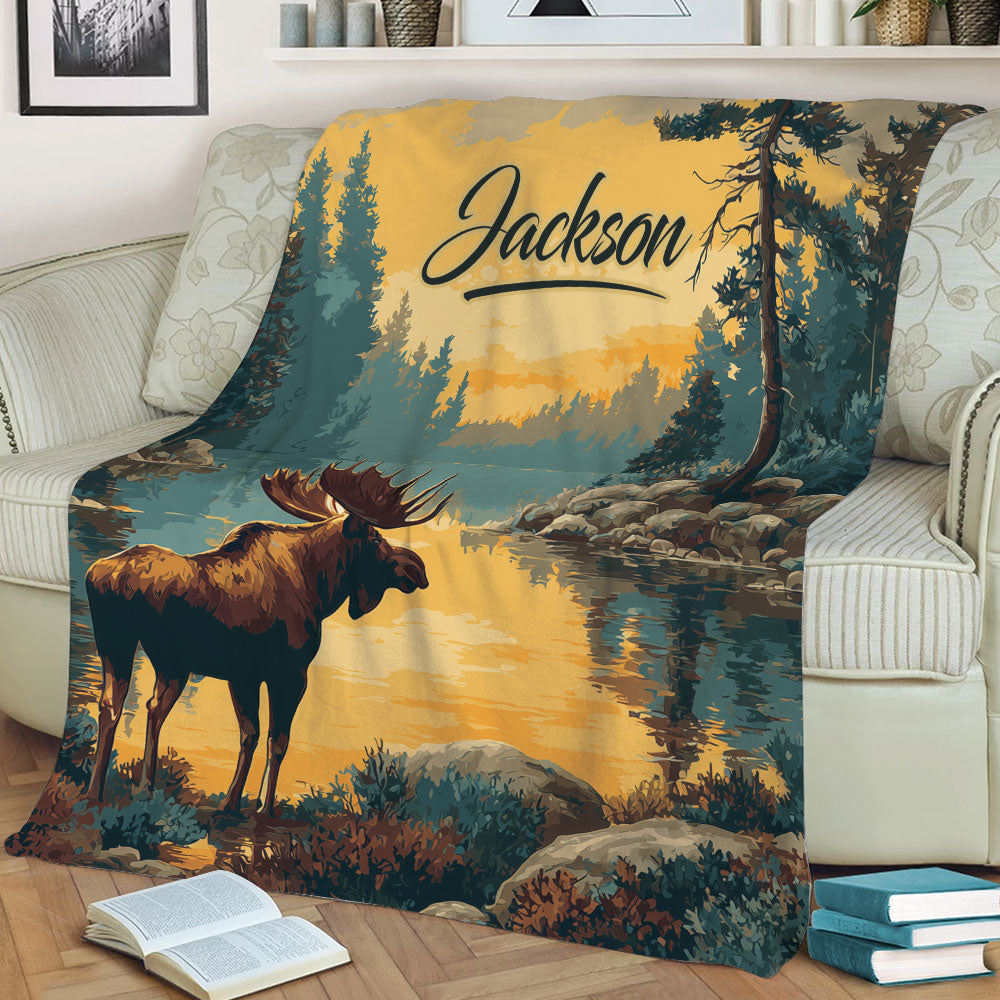 Close view of a moose throw blanket displayed on a couch with detailed woodland and lake artwork