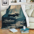 Moose blanket draped over a sofa with forest artwork, river scenery, and rustic woodland colors