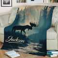 Rustic moose throw blanket displayed on a sofa with evergreen trees, mountain scenery, and a river