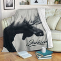 Moose blanket draped over a sofa with monochrome forest artwork for rustic living room decor