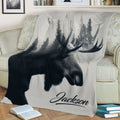 Close view of a moose throw blanket displaying detailed antlers and evergreen forest artwork