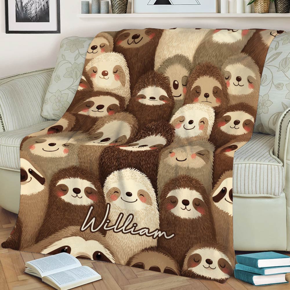 Close view of a sloth blanket displayed on a sofa with playful brown and cream artwork