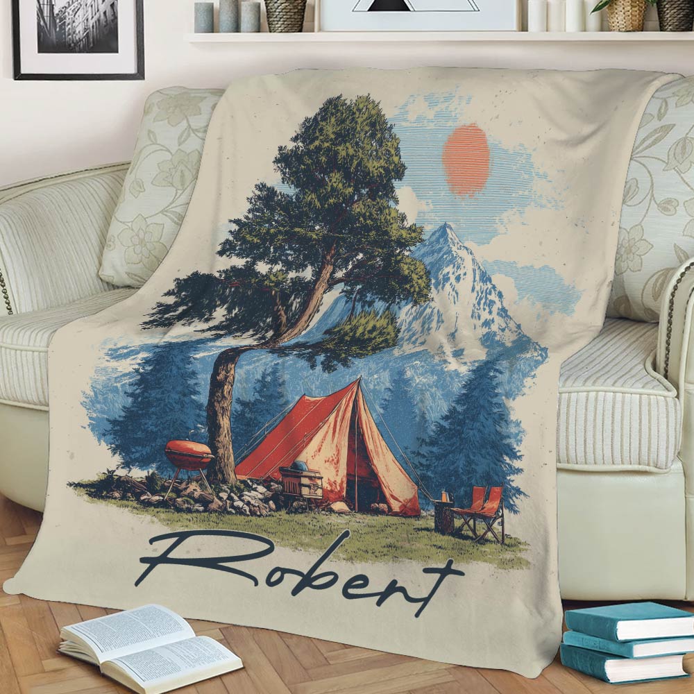 Close view of camping blanket artwork featuring a mountain, evergreen trees, red tent and sunny outdoor scene