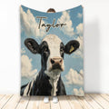 Black and white cow blanket with blue sky and cloud artwork displayed upright
