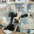 Cow throw blanket featuring a close-up black and white cow against a cloudy blue sky