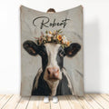 Custom cow blanket featuring a black and white cow with a colorful floral crown on a rustic background