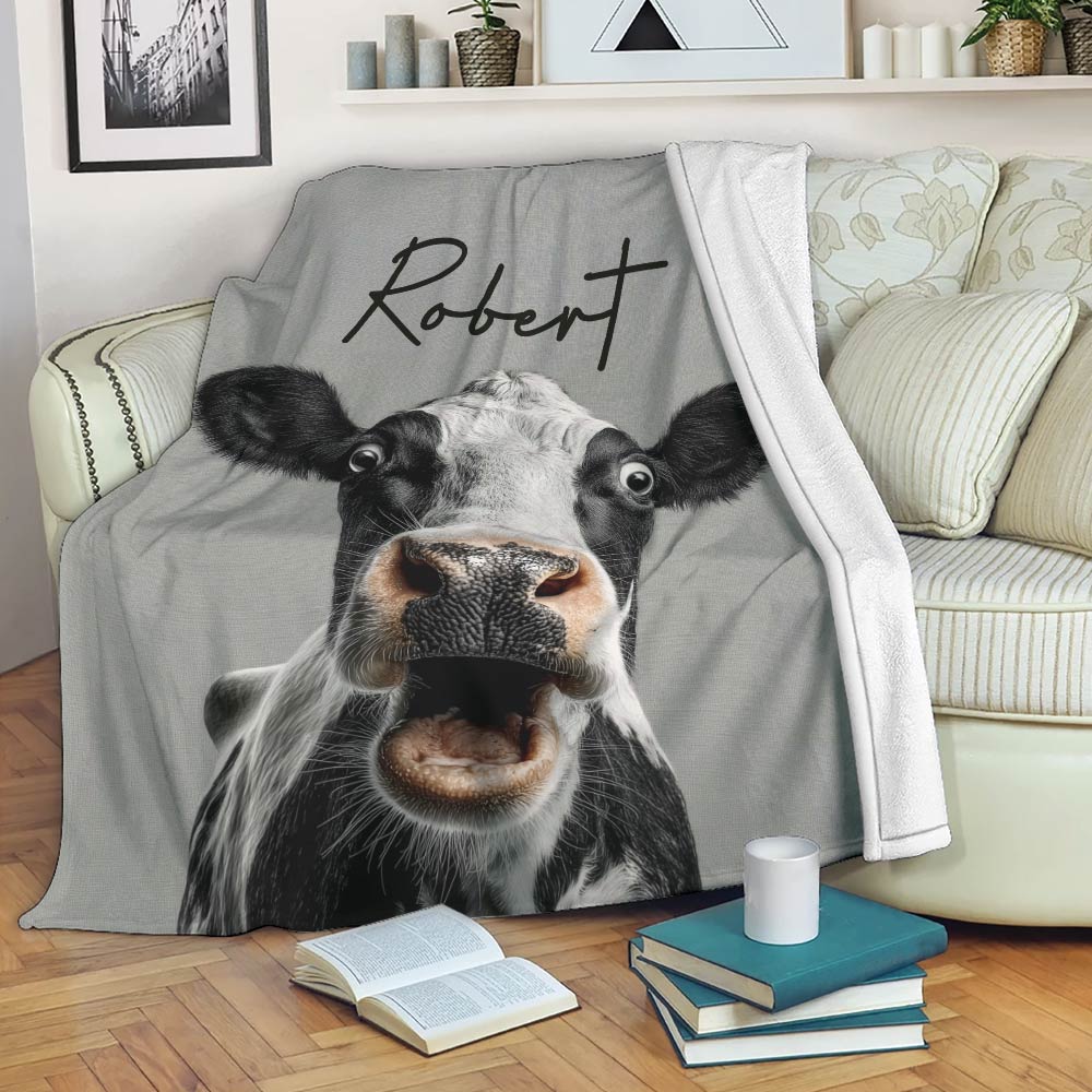 Black and white cow throw blanket displayed on a sofa in a cozy living room setting