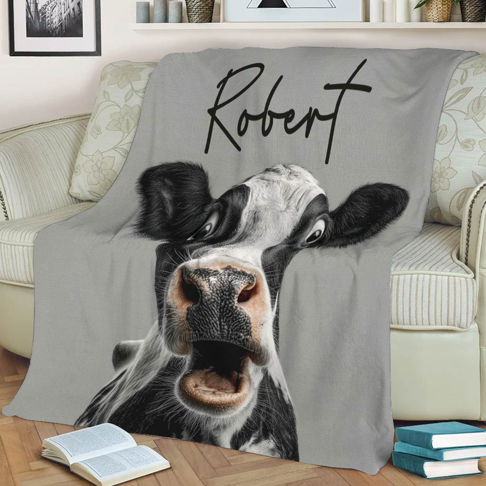 Funny cow throw blanket draped over a sofa with bold black and white farm animal artwork