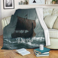 Viking blanket displayed on a sofa with dark longship artwork and stormy ocean waves