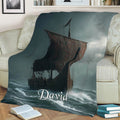 Viking throw blanket draped over a sofa, showing a Norse ship on a turbulent sea