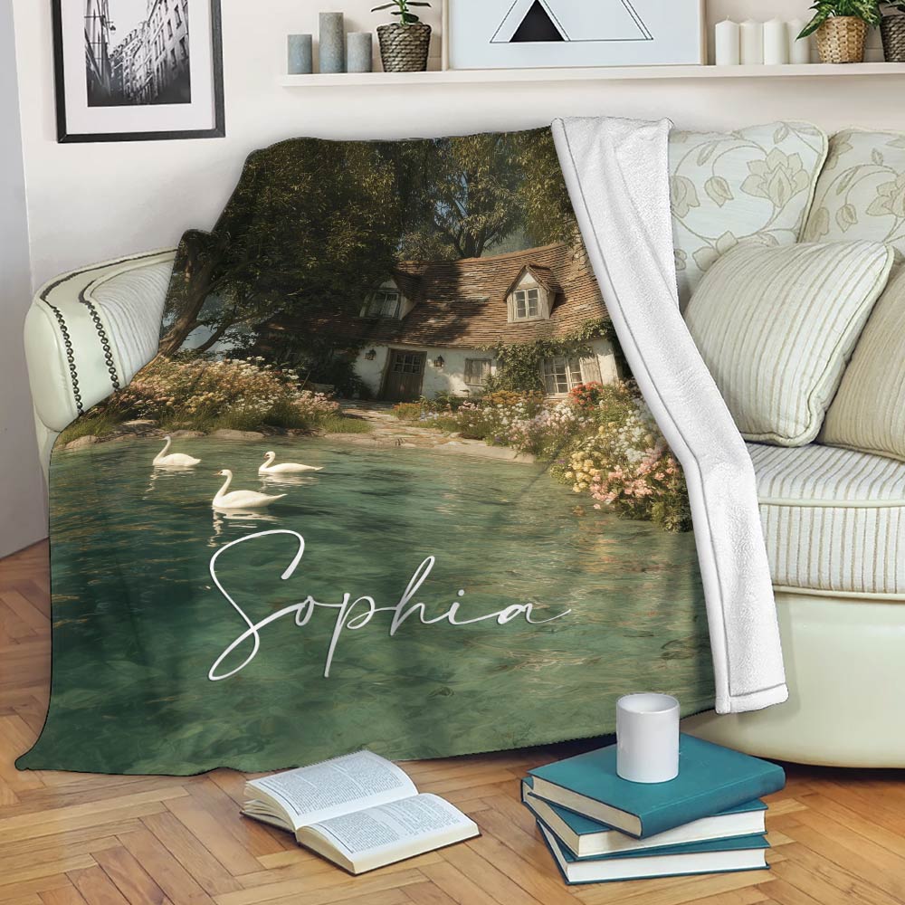Lake house throw blanket draped over a sofa with cottage, pond, swan, and garden artwork in calming green tones