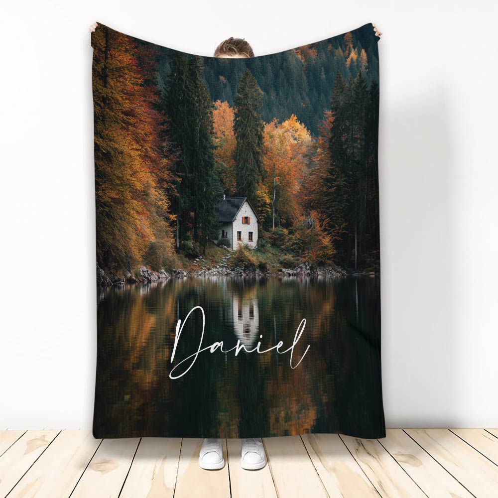 Lake house throw blanket featuring an autumn forest, quiet lake, and secluded cabin scene