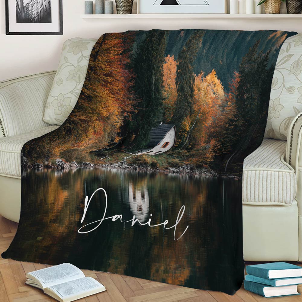 Lakeside cabin throw blanket displayed on a sofa with rich fall foliage and lake reflections