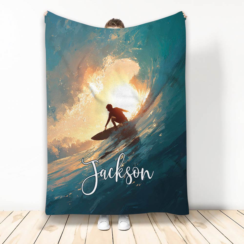 Surfing blanket with dramatic surfer silhouette riding a wave at sunset in teal and gold tones