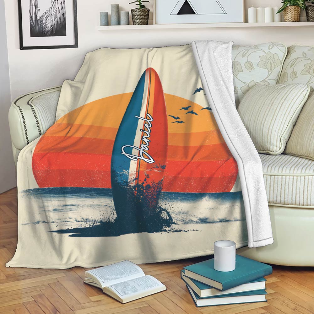 Surfboard beach throw blanket displayed on a sofa with retro sunset artwork and ocean waves
