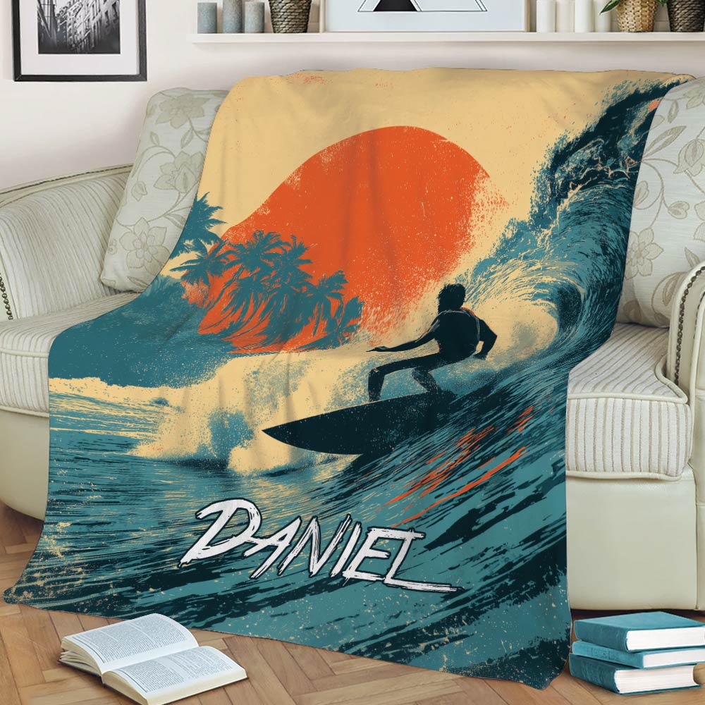 Surfing throw blanket draped over a chair, featuring a surfer, ocean wave, palms, and sunset