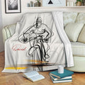 Bicycle throw blanket displayed on a sofa with expressive cyclist line art and yellow accents