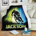 Bicycle throw blanket displayed on a sofa with bold cyclist artwork and colorful vertical background panels