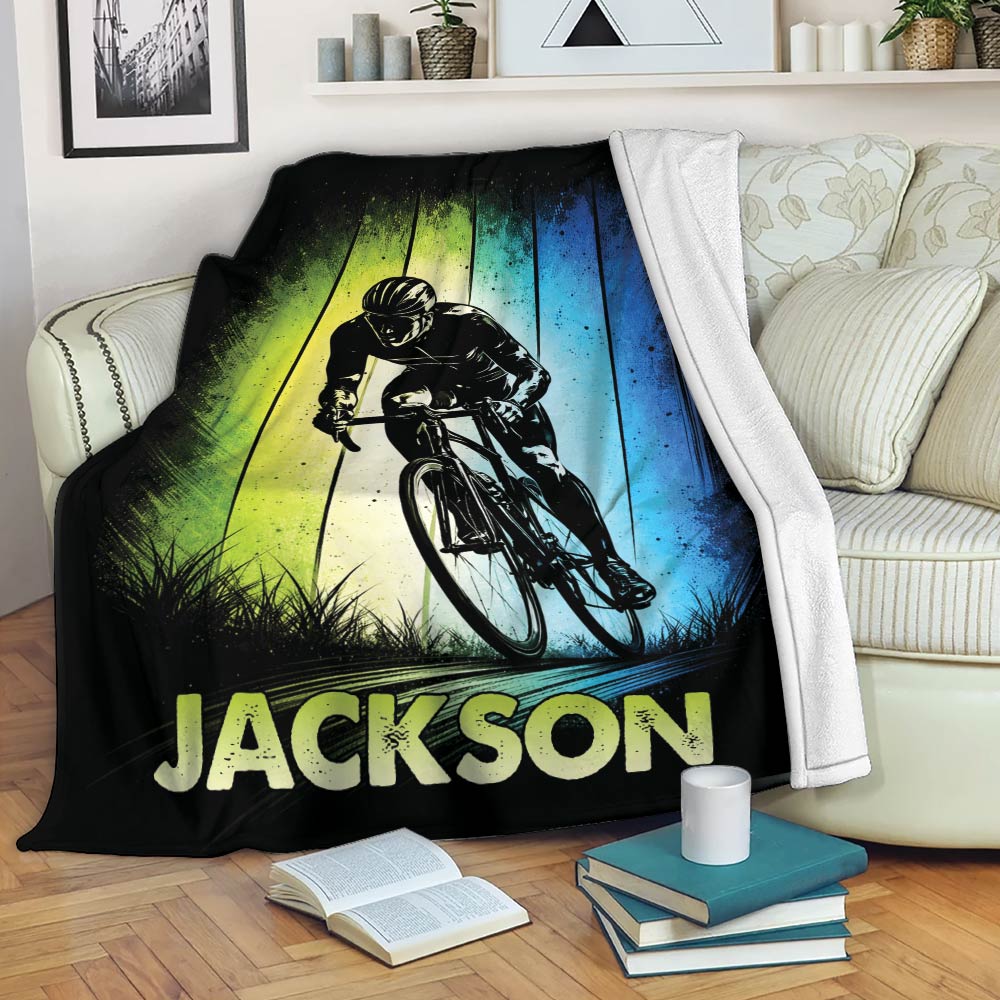 Bicycle throw blanket displayed on a sofa with bold cyclist artwork and colorful vertical background panels