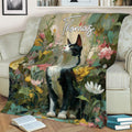 Black-and-white tuxedo cat blanket draped over an armchair with vibrant garden flowers