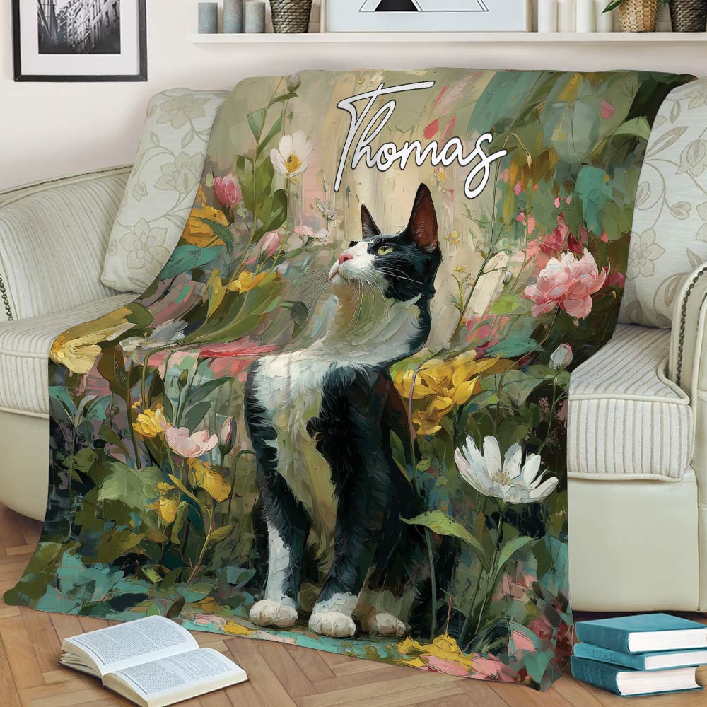 Black-and-white tuxedo cat blanket draped over an armchair with vibrant garden flowers