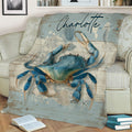 Close view of a blue crab throw blanket with seashells and ocean-inspired artwork