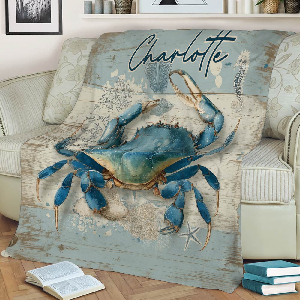 Close view of a blue crab throw blanket with seashells and ocean-inspired artwork