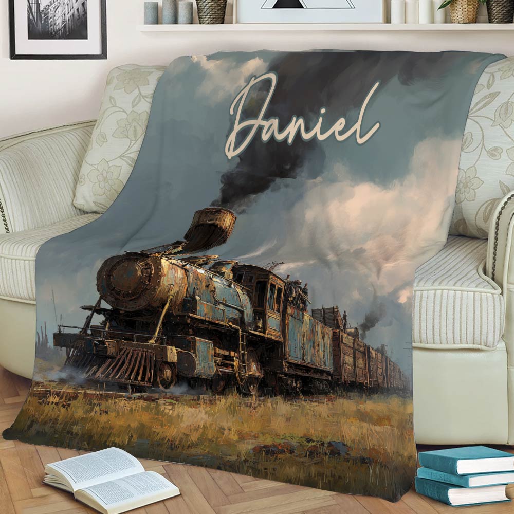 Steam train throw blanket displayed on a sofa with rustic railway artwork and a moody sky