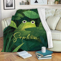 Frog throw blanket draped over a sofa with tropical green leaf artwork