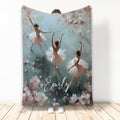 Ballet throw blanket featuring three ballerinas surrounded by soft pink flowers and painterly blue-green artwork