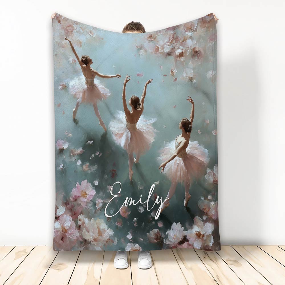 Ballet throw blanket featuring three ballerinas surrounded by soft pink flowers and painterly blue-green artwork