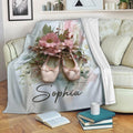 Ballet throw blanket displayed on a sofa with pink pointe shoes and watercolor flowers