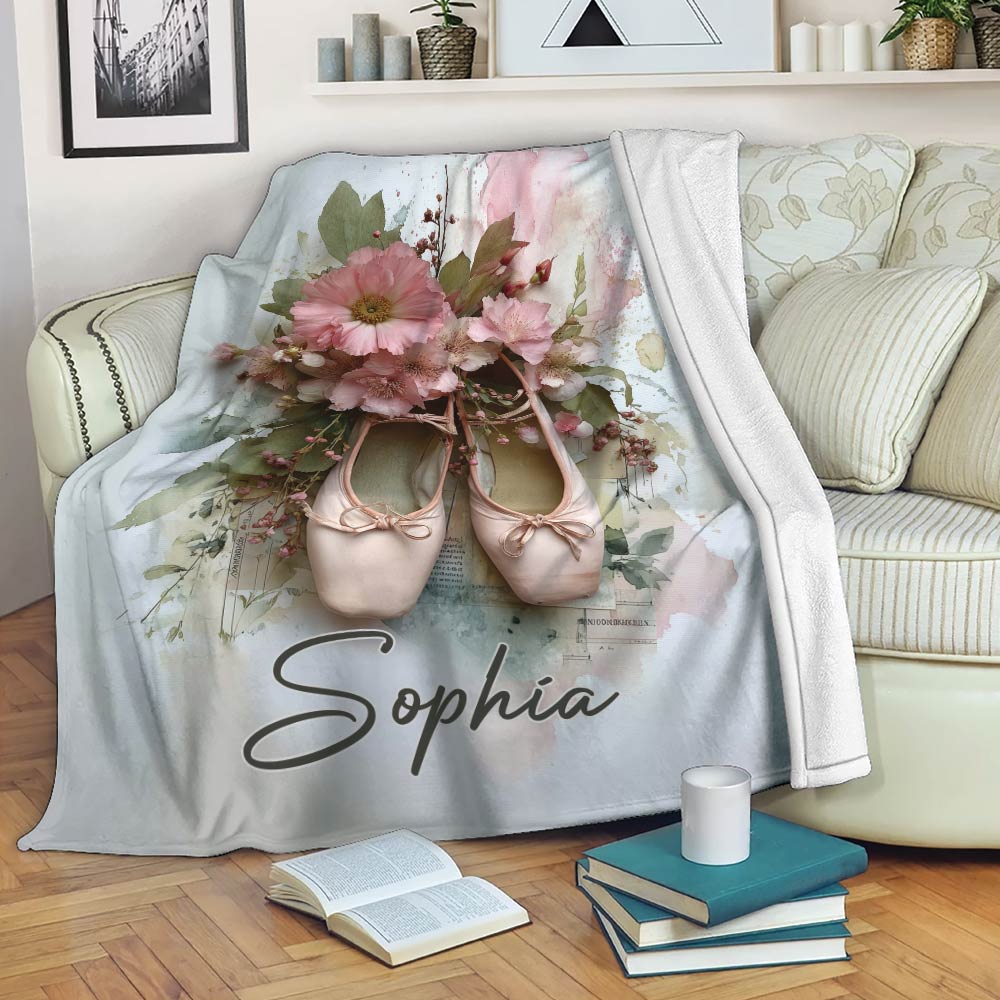 Ballet throw blanket displayed on a sofa with pink pointe shoes and watercolor flowers