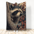 Raccoon throw blanket featuring a detailed woodland raccoon peeking around a tree among autumn leaves