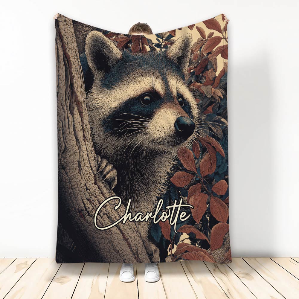 Raccoon throw blanket featuring a detailed woodland raccoon peeking around a tree among autumn leaves